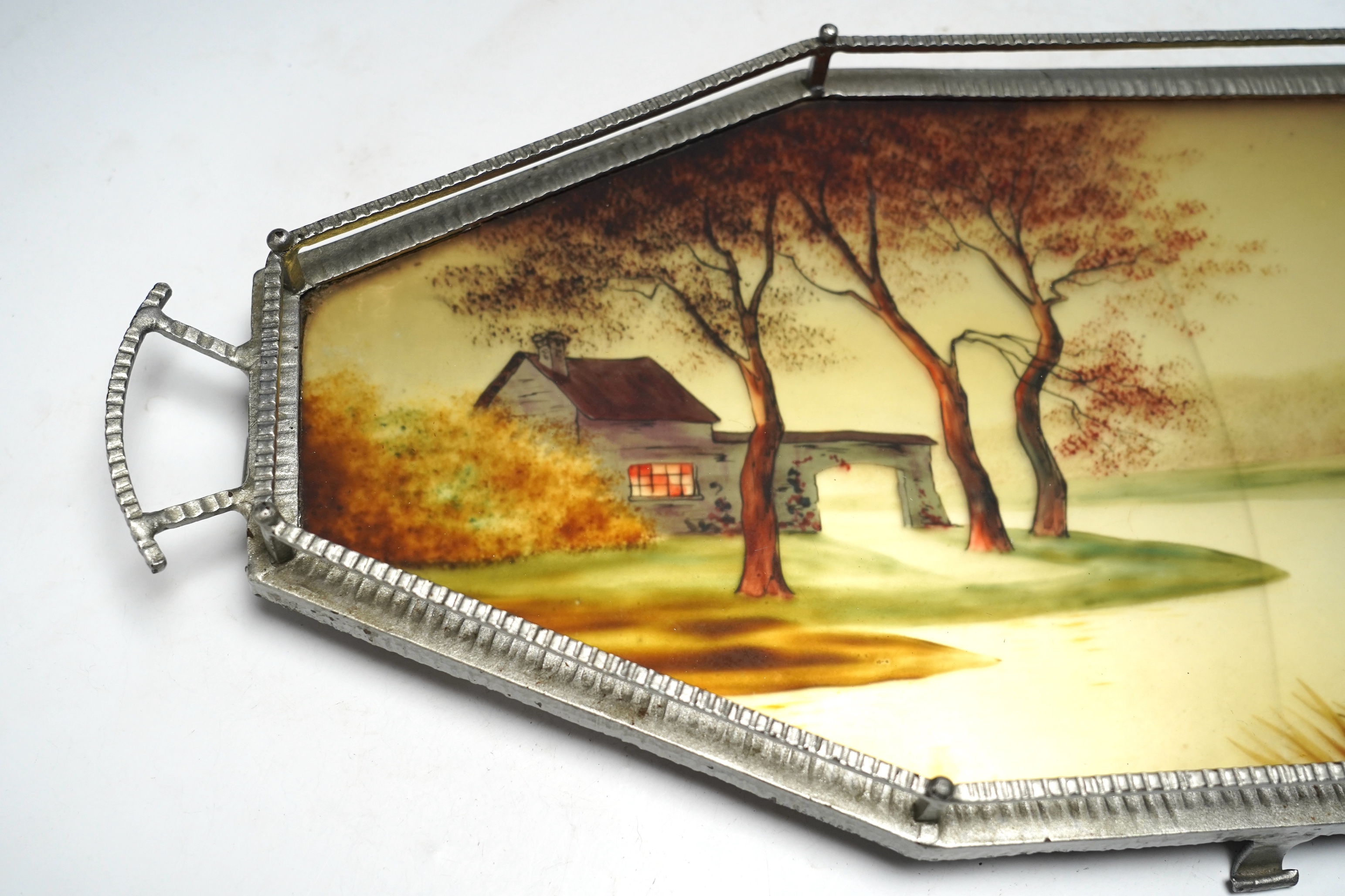 An Art Deco reverse painted and wrought iron tray, with a gallery, centered with a reverse painted landscape scene, signed 'Germonde', 70cm. Condition - damaged
